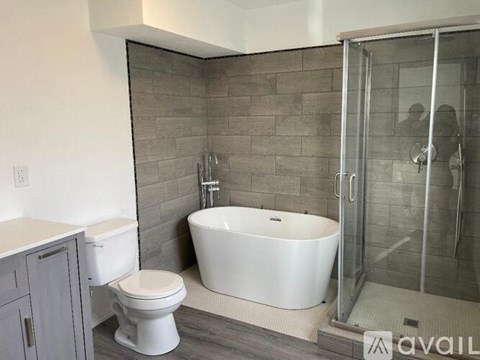 A bathroom with a white tub, toilet, and a walk-in shower.