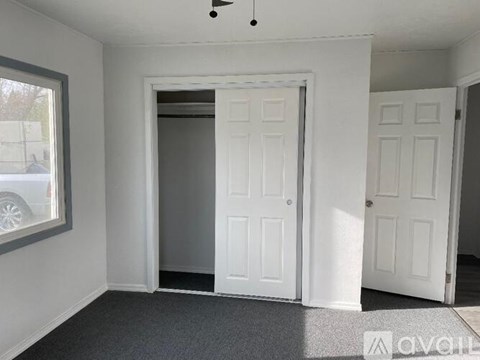 A room with a white door and a window on the left.