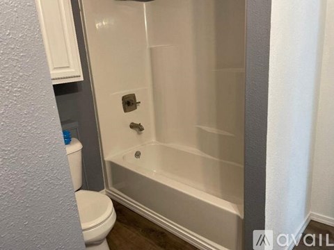 A white bathroom with a toilet, tub, and a white wall.