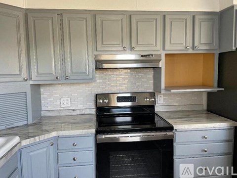 A kitchen with a stove top oven and cabinets.