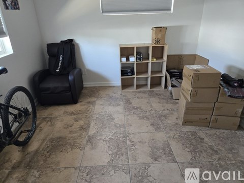 A room with a black chair, a bicycle, and cardboard boxes.