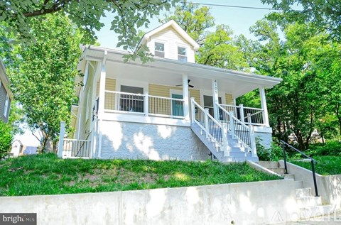 A house with a white porch and stairs leading up to the front door.