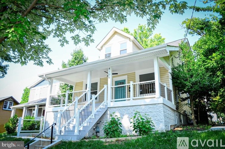 A two-story house with a white porch and green shutters.