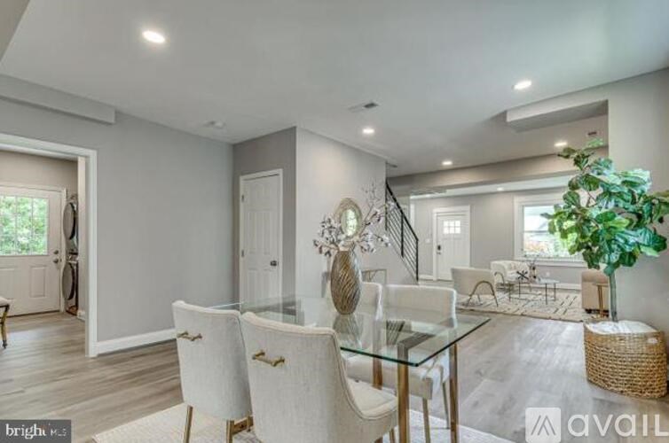 A modern dining room with a glass table and white chairs.