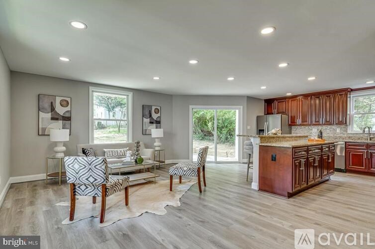 A modern kitchen and living room with a wooden floor and a cowhide rug.