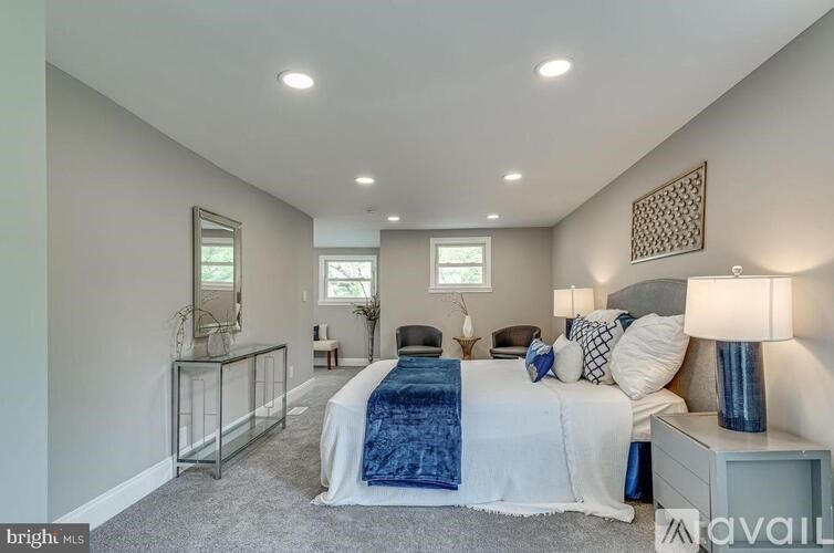 A bedroom with a bed, nightstand, and two windows.