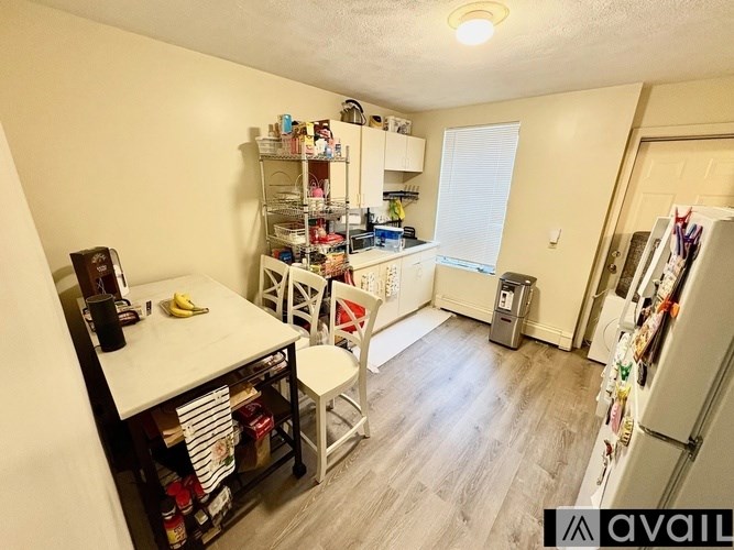 A kitchen with a refrigerator, a table, and a chair.