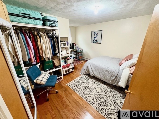 A person is sleeping on a bed in a room with a wardrobe and a chair.