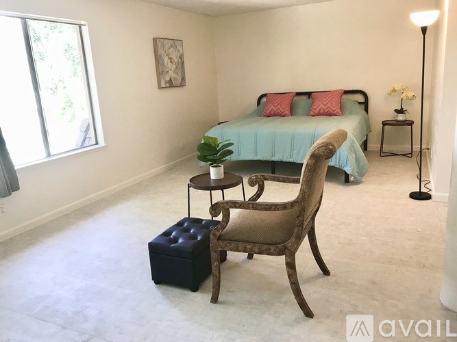 A bedroom with a bed, chair, and lamp.