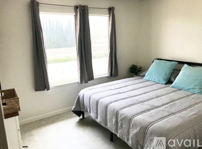 A bedroom with a large bed and a window with curtains.