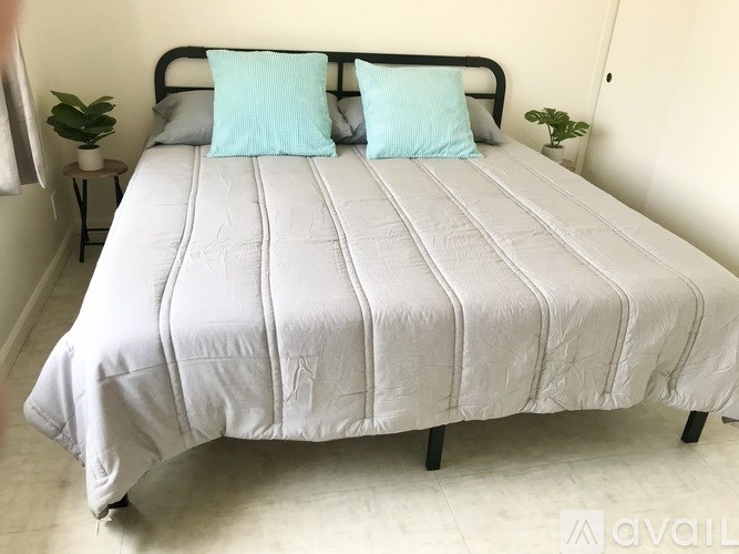 A bed with a grey cover and two blue pillows is in the image.