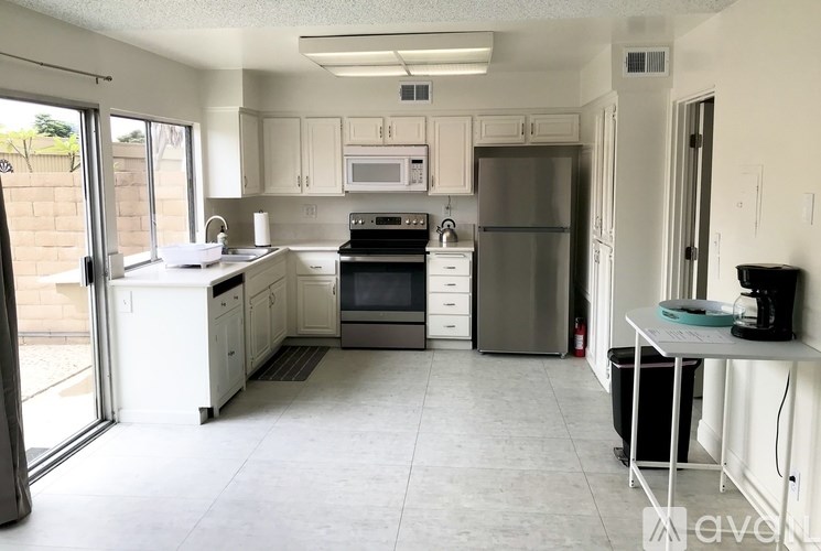 A kitchen with white appliances and cabinets.