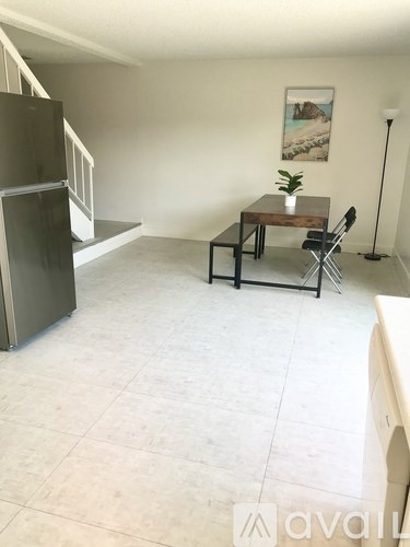 A kitchen with a fridge, table and chairs.