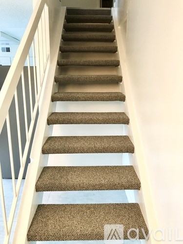 A staircase with a carpeted runner and white railings.