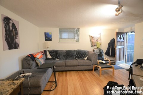 A living room with a grey couch and a wooden floor.