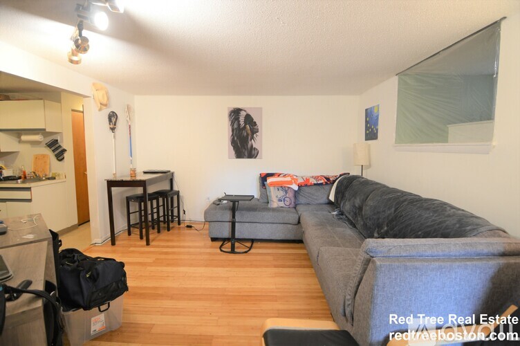 A living room with a grey couch and a black bag on the floor.