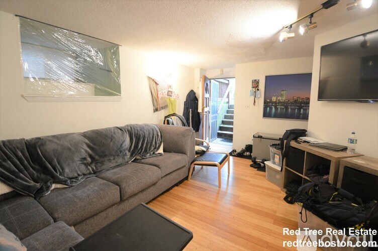 A living room with a grey couch and a black laptop on a black table.
