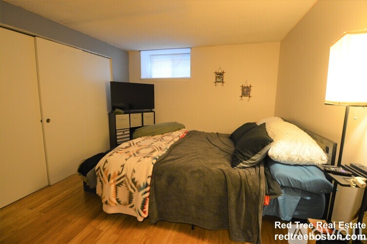A bedroom with a bed, a dresser, and a window.