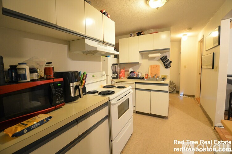 A kitchen with white cabinets and appliances.