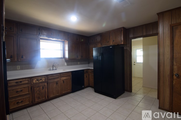 A kitchen with a black fridge and wooden cabinets.