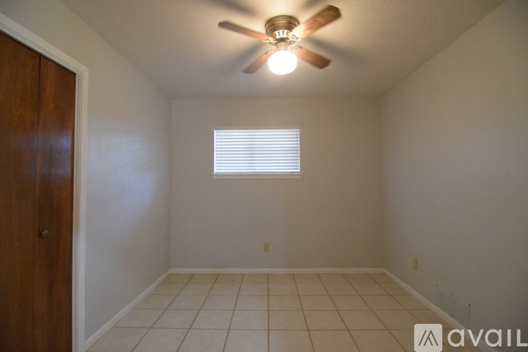 A grassy field with trees and a building in the background.