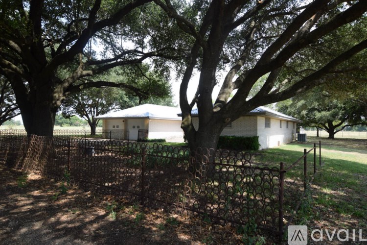 A house is surrounded by a fence and trees.
