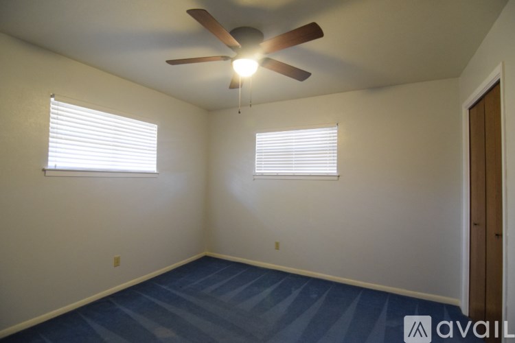 A room with a ceiling fan and two windows.