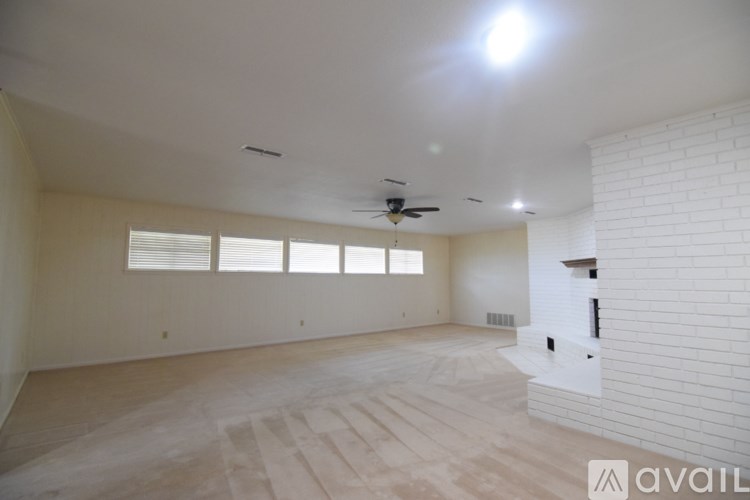 A spacious living room with a fireplace and a ceiling fan.