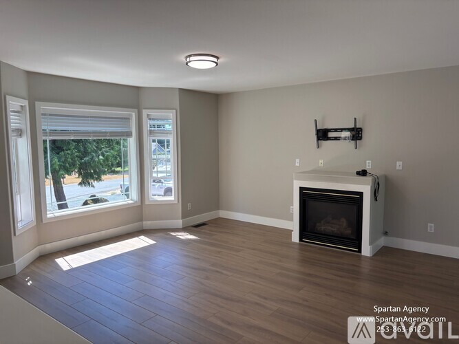 A living room with a fireplace and a window overlooking a street.
