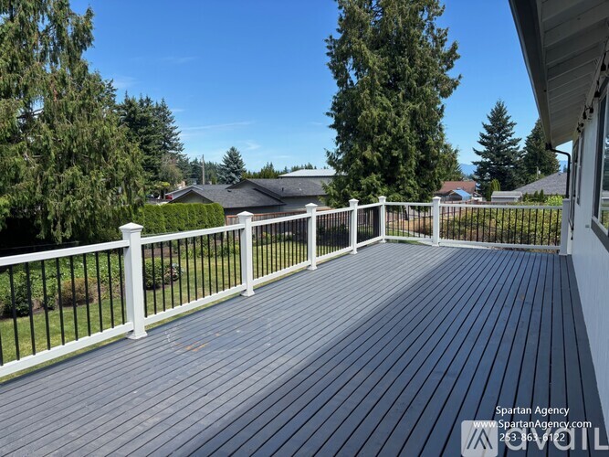 A wooden deck with a white railing and trees in the background.