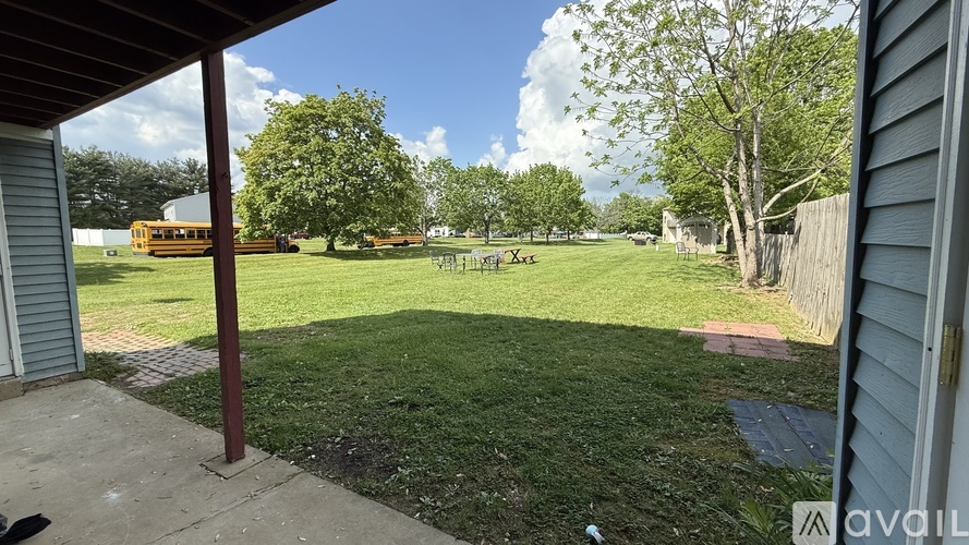 A backyard with a green lawn and a playground in the background.