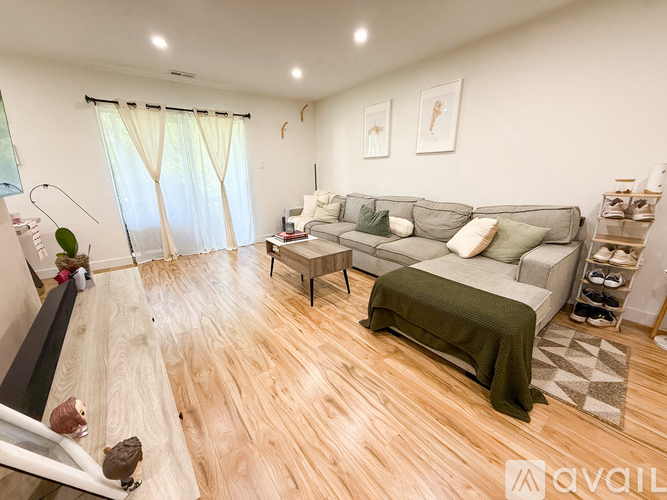 A living room with a grey couch and a green blanket.