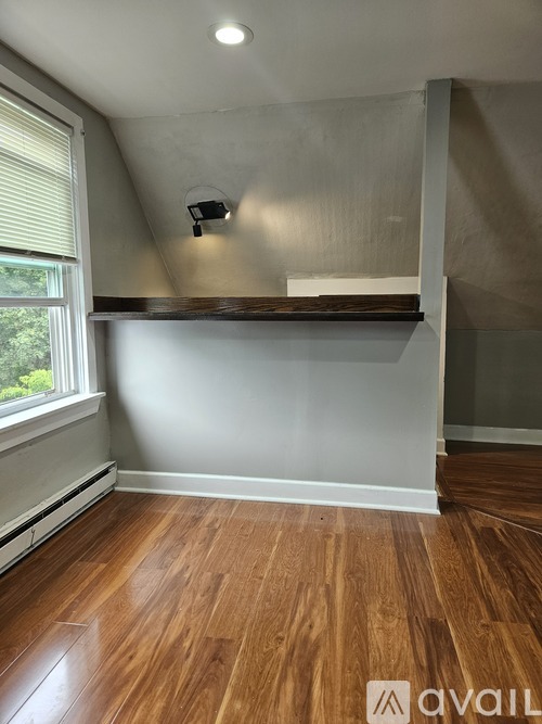 A room with wooden floors and a window with blinds.