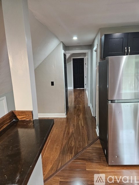 A kitchen with a stainless steel refrigerator and wooden flooring.
