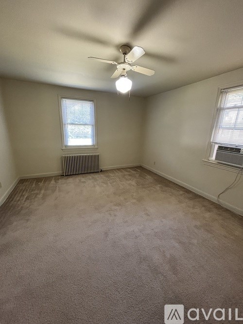 A room with a carpeted floor, a ceiling fan, and a window with blinds.