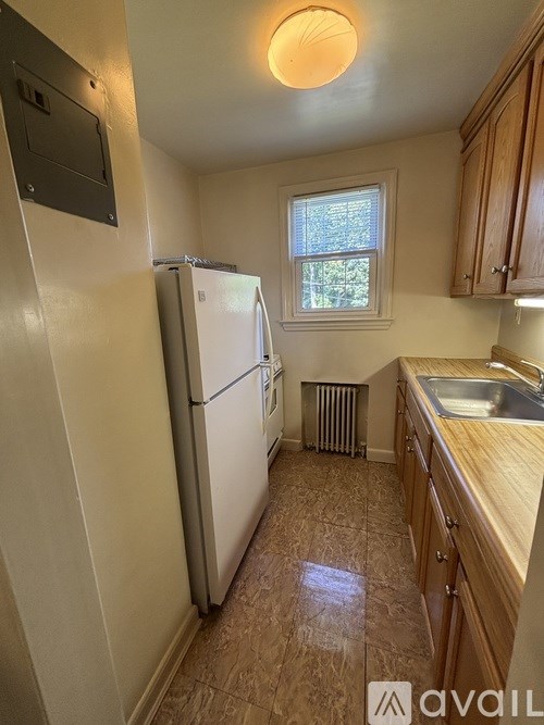 A kitchen with a white fridge and wooden cabinets.