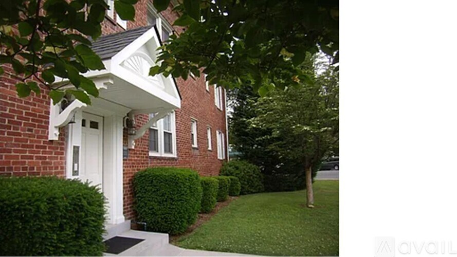 A house with a white door and windows is surrounded by green bushes.