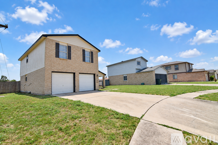 A house with a garage is surrounded by a grassy area and a driveway.