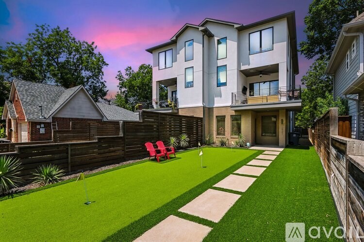 A modern house with a well-manicured lawn and a wooden fence.