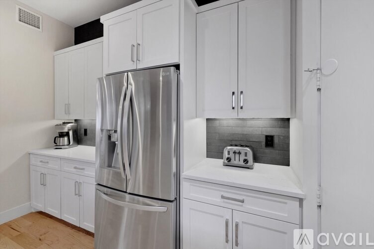 A modern kitchen with a stainless steel refrigerator and white cabinets.