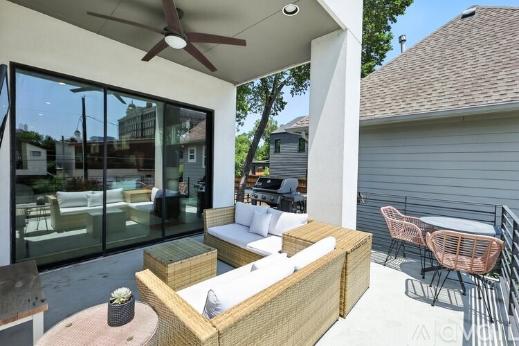 A patio with a wicker sofa and a ceiling fan.