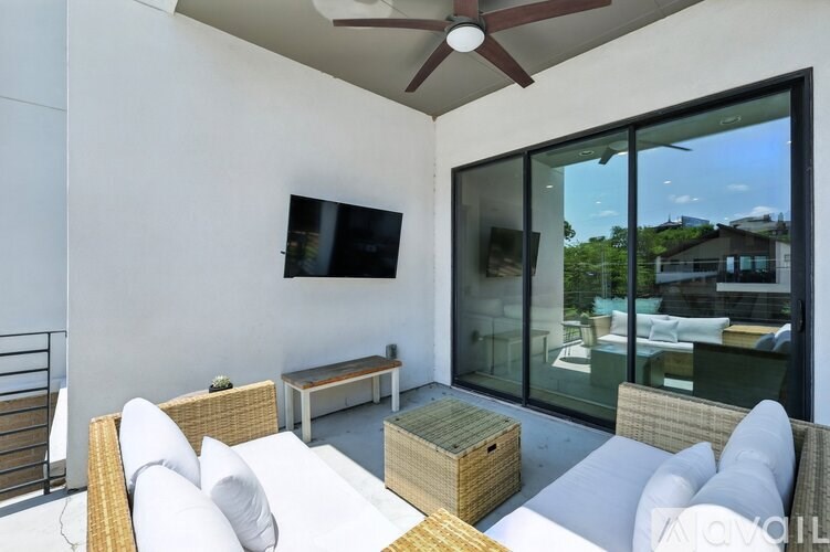 A patio with a white couch, a wicker table, and a ceiling fan.