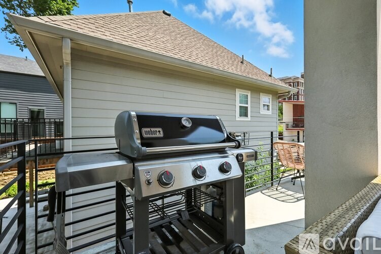 A Weber grill is on a patio outside a house.