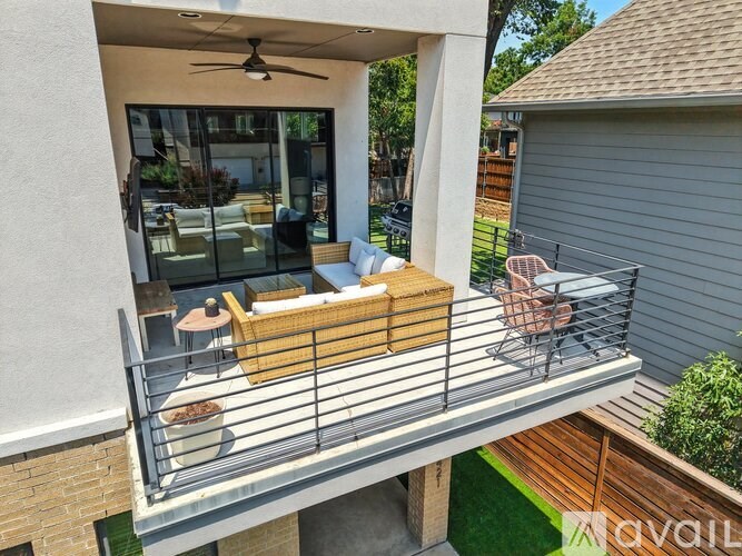 A balcony with a table and chairs overlooking a backyard.