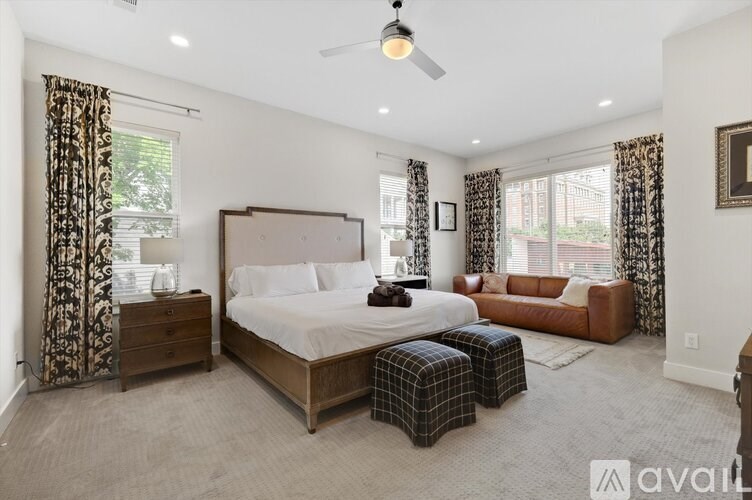 A bedroom with a large bed, a brown sofa, and a ceiling fan.