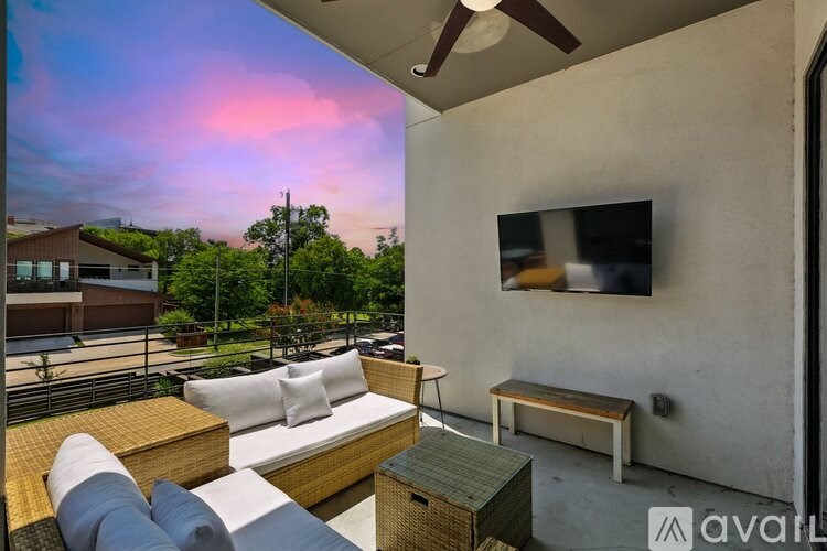 A patio with a couch, table, and television with a view of the sky.