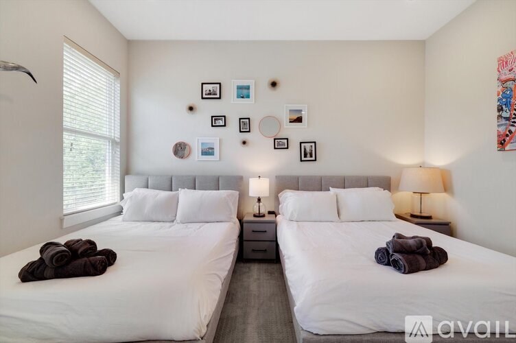 A bedroom with two beds, each with a white bedspread and a brown towel on top.
