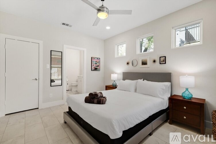A bedroom with a large bed, a ceiling fan, and a nightstand with a lamp.