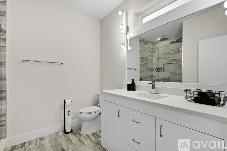 A bathroom with a toilet, sink, and mirror.