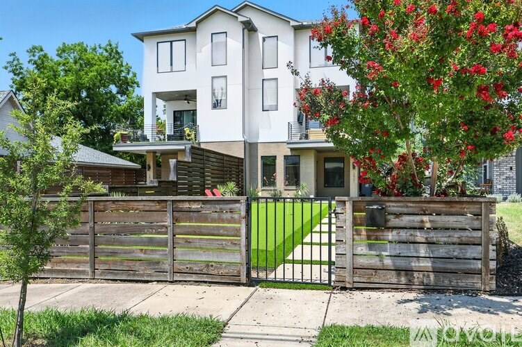 A white two-story house with a black gate and a green lawn in front.